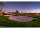 Golf course sand trap with rake and homes in the background at dusk at 23206 N Del Monte Dr, Sun City West, AZ 85375