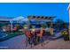 Outdoor kitchen and dining area with pergola, comfortable seating, and beautiful landscaping at 26398 W Cat Balue Dr, Buckeye, AZ 85396