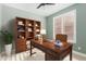 Elegant office featuring a wooden desk, a tufted chair, and ample natural light from shuttered windows at 41512 N Tangle Ridge Ct, Anthem, AZ 85086