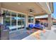 Covered patio features a sectional sofa, TV, and sliding glass doors leading to the pool at 44049 W Palo Nuez St, Maricopa, AZ 85138