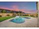 Inviting backyard oasis featuring a kidney-shaped pool, lush landscaping, and a covered patio at 44049 W Palo Nuez St, Maricopa, AZ 85138
