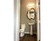 Stylish powder room with pedestal sink, unique mirror, and dark flooring at 5822 E Bramble Berry Ln, Cave Creek, AZ 85331