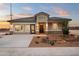 Charming single story home with desert landscaping, stone accents and a concrete driveway at sunset at 1167 W Chimes Tower Dr, Casa Grande, AZ 85122