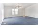 Simple bedroom with blue carpet, ceiling fan, and exterior view at 12866 W Sun Ave, Eloy, AZ 85131