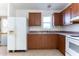 Kitchen with wood cabinets, white appliances, and a window view at 12866 W Sun Ave, Eloy, AZ 85131