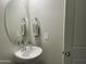 Small bathroom with pedestal sink, oval mirror, and towel racks at 35262 W San Ildefanso Ave, Maricopa, AZ 85138