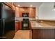 Kitchen features dark wood cabinets, granite counters, and black appliances at 5450 E Deer Valley Dr # 4201, Phoenix, AZ 85054