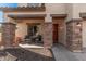 Covered porch with stone columns, two wicker chairs, and a red door at 14570 N 142Nd Ln, Surprise, AZ 85379