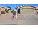 Tan house with a two-car garage and nicely landscaped yard at 15350 W Mauna Loa Ln, Surprise, AZ 85379