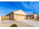 Tan house with a two-car garage and a wooden gate at 17662 W Daley Ln, Surprise, AZ 85387