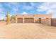 Three-car garage with tan stucco exterior and a large cactus nearby at 22605 W Baker Dr, Wittmann, AZ 85361