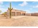 Three-car garage with tan stucco exterior and a large cactus nearby at 22605 W Baker Dr, Wittmann, AZ 85361