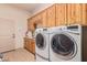 Laundry room with washer, dryer, and wood cabinets at 22605 W Baker Dr, Wittmann, AZ 85361