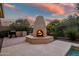 Outdoor fireplace with seating area and beautiful sunset view at 40822 N Harbour Town Way, Anthem, AZ 85086