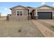 Charming single-story home with a brick driveway, desert landscaping and a dark blue garage door at 4727 N 177Th Dr, Goodyear, AZ 85395