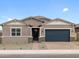 Charming single-story home with a brick driveway, desert landscaping and a dark blue garage door at 4727 N 177Th Dr, Goodyear, AZ 85395