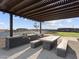 Outdoor kitchen under a shaded pergola featuring a built-in grill and picnic table beside a basketball court at 4727 N 177Th Dr, Goodyear, AZ 85395