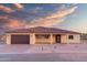 Charming single-story home with desert landscaping, a terracotta roof, and a brown garage door complements the home's neutral palette at 125 Ironwood Pl, Wickenburg, AZ 85390