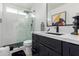 Bathroom with dark vanity, white tile and walk-in shower at 1638 E Hackamore St, Mesa, AZ 85203