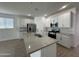 Well-lit kitchen with stainless appliances, white cabinets, backsplash, and a large island for food prep and entertaining at 22859 E Lords Way, Queen Creek, AZ 85142