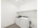 A bright laundry room featuring a white washer and dryer set, complemented by a shelf for storage at 35581 N Thicket Way, San Tan Valley, AZ 85144