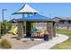 Community picnic area with stone pillars, a shelter, BBQ, and playground in a well-maintained park setting at 35581 N Thicket Way, San Tan Valley, AZ 85144