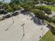 Aerial view of the community's well-lit basketball court, surrounded by lush trees and a picnic area at 37042 W Prado St, Maricopa, AZ 85138