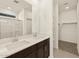 Bathroom featuring dual sinks, white countertops, dark cabinets, and a glass shower enclosure at 37042 W Prado St, Maricopa, AZ 85138