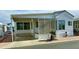 White single-wide manufactured home with covered porch and screened patio at 7750 E Broadway Rd # 232, Mesa, AZ 85208