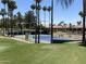 Community tennis court nestled amongst palm trees and green lawns at 11111 E Elmhurst Dr, Sun Lakes, AZ 85248