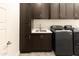 Modern laundry room with dark cabinetry and utility sink at 3928 E Crittenden Ln, Phoenix, AZ 85018