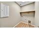 Functional laundry room with tile floors, shelf, utility connections, and access panel at 19026 W Stella Ave, Waddell, AZ 85355