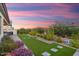 Backyard with artificial turf, rock beds, and a wrought iron fence, underneath a sunset sky at 20363 W Coolidge St, Buckeye, AZ 85396