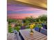 Outdoor patio with dining table and chairs, lounge chairs, manicured landscaping, and a vibrant sunset at 20363 W Coolidge St, Buckeye, AZ 85396