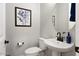 Stylish powder room with a pedestal sink, round mirror, and tasteful artwork, offering a modern and clean design at 20363 W Coolidge St, Buckeye, AZ 85396