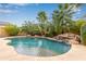 Relaxing kidney-shaped pool with a waterfall and palm trees at 21525 E Camacho Rd, Queen Creek, AZ 85142