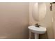 Small powder room with pedestal sink and oval mirror at 21525 E Camacho Rd, Queen Creek, AZ 85142