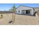 Wide view of the gravel landscaped backyard featuring a covered patio and small newly planted trees at 2324 W Moody Trl, Phoenix, AZ 85041