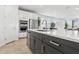Modern kitchen island with a marble countertop, stainless steel sink, and dark gray cabinets at 2324 W Moody Trl, Phoenix, AZ 85041