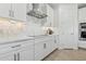 Well-lit kitchen with modern appliances, white cabinetry, and a decorative tile backsplash at 2324 W Moody Trl, Phoenix, AZ 85041