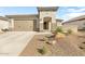 Tan colored house with a two-car garage and drought tolerant landscaping at 26448 W Kimberly Way, Buckeye, AZ 85396