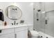 Modern bathroom with a round mirror, walk-in shower, and white cabinets at 34083 N Paseo Grande Dr, Queen Creek, AZ 85144