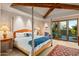 Bright main bedroom with a wooden four-poster bed and access to a patio at 39863 N 105Th Pl, Scottsdale, AZ 85262