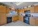 Kitchen with oak cabinets, black appliances, and tile floor at 43568 W Bedford Dr, Maricopa, AZ 85138