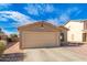 Tan house with a two-car garage and desert landscaping at 7244 S Sunrise Way, Buckeye, AZ 85326