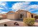 Tan house with a two-car garage and desert landscaping at 7244 S Sunrise Way, Buckeye, AZ 85326