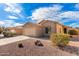 Tan house with a two-car garage and desert landscaping at 7244 S Sunrise Way, Buckeye, AZ 85326