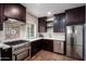 Modern kitchen with dark wood cabinets, stainless steel appliances, and tile backsplash at 903 W Mackenzie Dr, Phoenix, AZ 85013