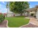 Landscaped backyard with artificial turf, covered patio, and mature tree at 4337 E Corral St, Phoenix, AZ 85044