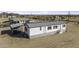 Aerial view of a white manufactured home with gray trim, gray roof, and a large yard at 6326 N Deer Trl, Maricopa, AZ 85139